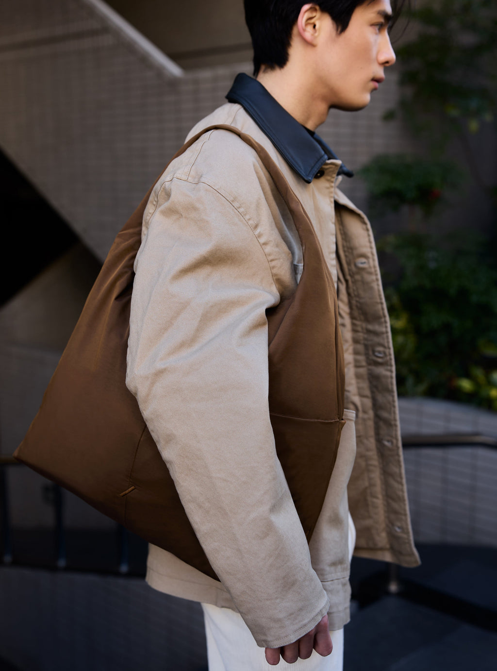 Man carrying the Arc slouchy hobo-style shoulder bag in chocolate brown nylon