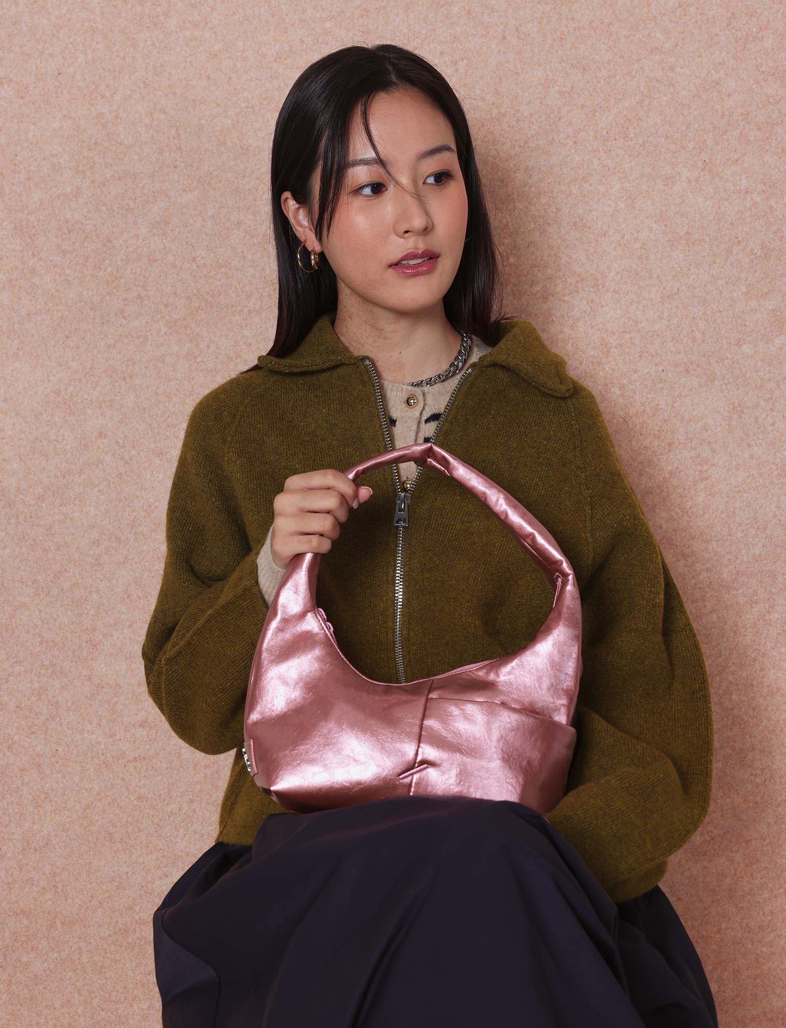 Woman holding the Mini Arc slouchy hobo-style shoulder bag in metallic pink vegan leather for errands, weekends and everyday use