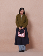 Woman holding the Mini Arc slouchy hobo shoulder bag in metallic pink vegan leather