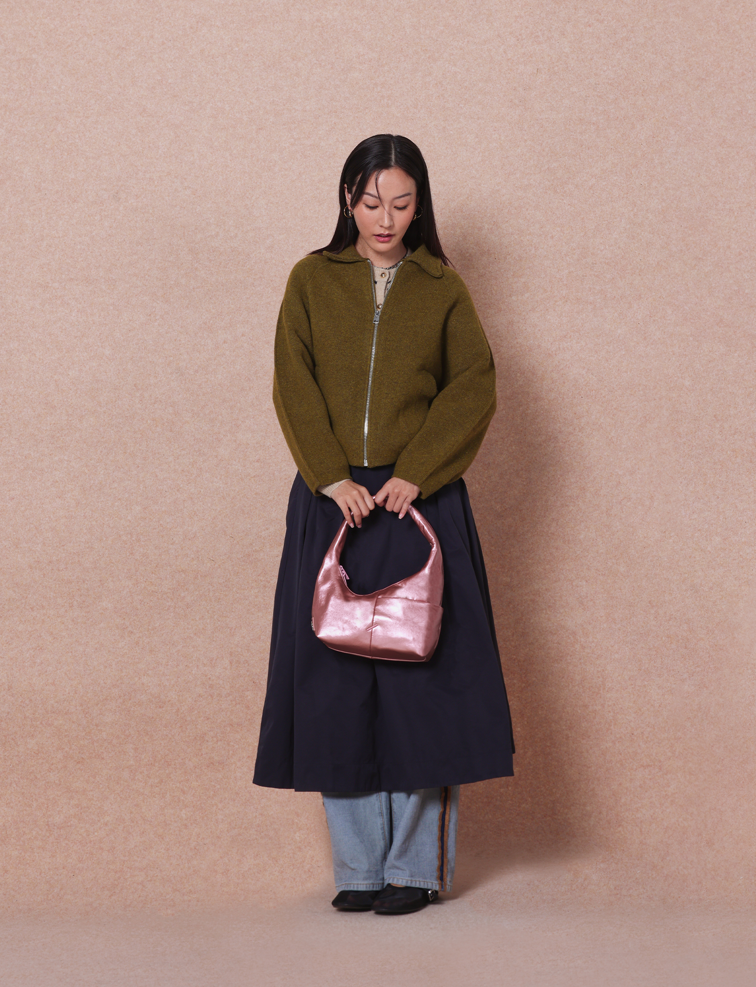 Woman holding the Mini Arc slouchy hobo shoulder bag in metallic pink vegan leather