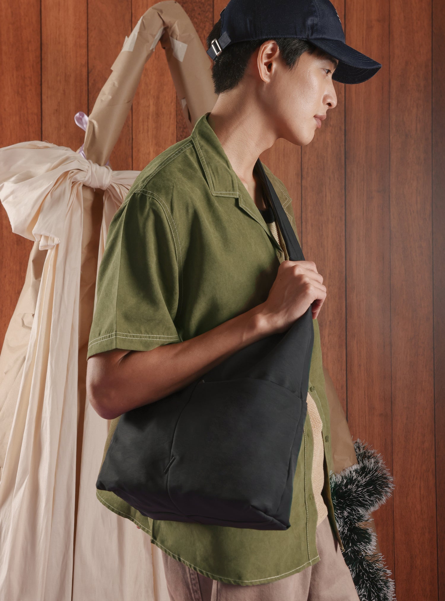 Man carrying the Midi Arc unisex slouchy hobo bag in black nylon as crossbody wear