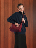 Woman carrying the Midi Arc slouchy hobo bag in wine red vegan leather as crossbody wear