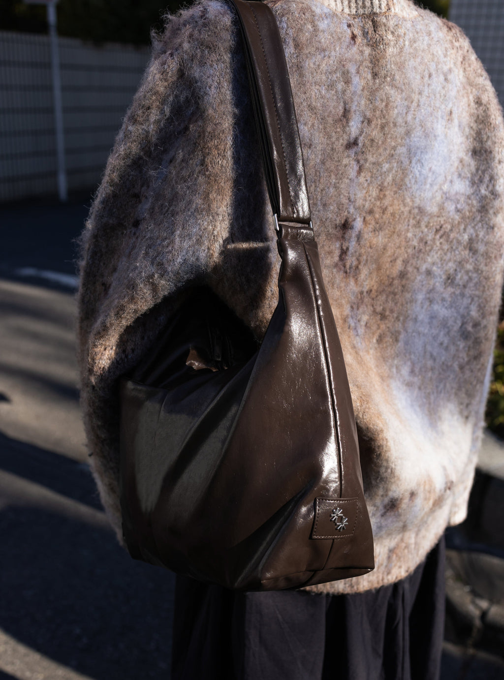 Woman carrying the Midi Arc slouchy hobo bag in dark brown vegan leather as shoulder bag