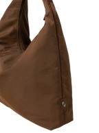 Close-up of the Arc hobo-style bag in chocolate brown nylon, showing metal logo emblem