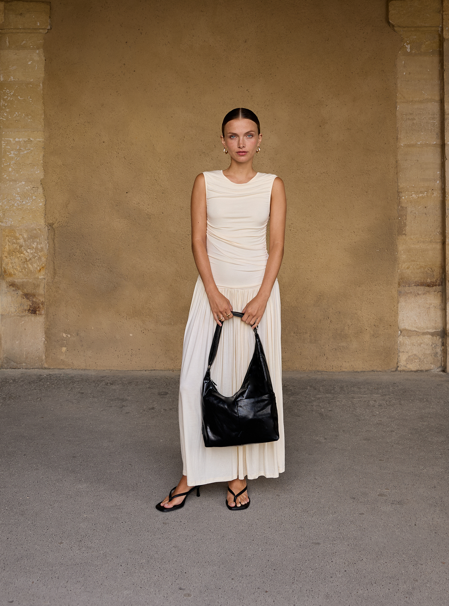 Woman holding the Midi Arc slouchy hobo bag in black vegan leather for work, travel and everyday use