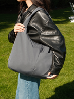 Woman holding the Arc slouchy hobo-style bag in grey nylon for work and travel