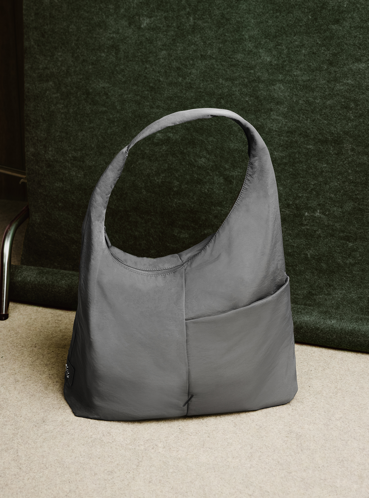 Woman holding the Arc slouchy hobo-style bag in grey nylon for work and office