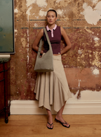 Woman carrying the Midi Arc slouchy hobo-style bag in beige nylon as shoulder bag for work, travel and everyday use
