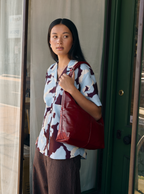 Woman carrying the Midi Arc slouchy hobo bag in wine red vegan leather as shoulder bag