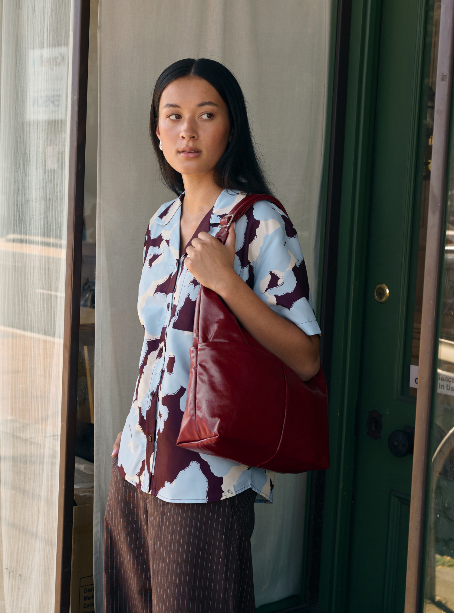 Woman carrying the Midi Arc slouchy hobo bag in wine red vegan leather as shoulder bag