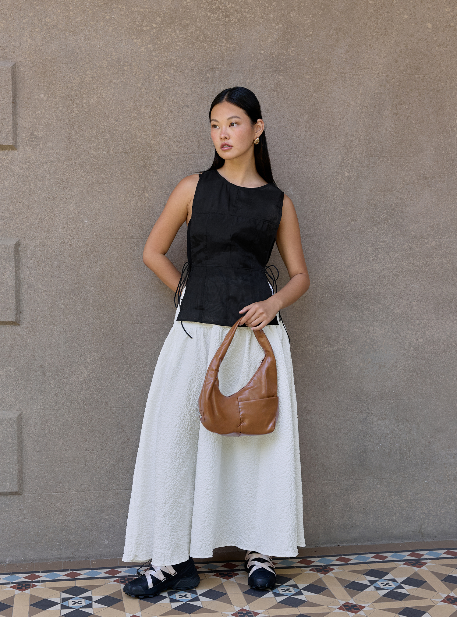 Woman carrying the Mini Arc slouchy hobo shoulder bag in warm brown vegan leather