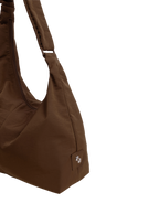 Close-up of the Midi Arc hobo-style bag in chocolate brown nylon, showing metal logo emblem