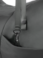 Exterior pocket of the Midi Arc hobo-style bag in dark grey nylon, with concealed snap loop