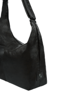 Close-up of the Midi Arc hobo-style bag in matte black vegan leather, showing metal logo emblem