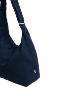 Close-up of the Midi Arc hobo-style bag in navy nylon, showing metal logo emblem