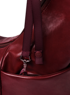 Exterior pocket of the Midi Arc hobo-style bag in wine red vegan leather, with concealed snap loop
