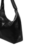 Close-up of the Midi Arc hobo-style bag in black vegan leather, showing metal logo emblem