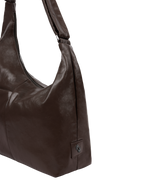 Close-up of the Midi Arc hobo-style bag in dark brown vegan leather, showing metal logo emblem