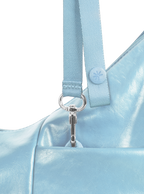 Exterior pocket of the Mini Arc hobo-style shoulder bag in pale blue vegan leather, with concealed snap loop