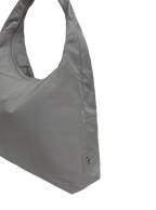 Close-up of the Arc hobo-style bag in grey nylon, showing metal logo emblem